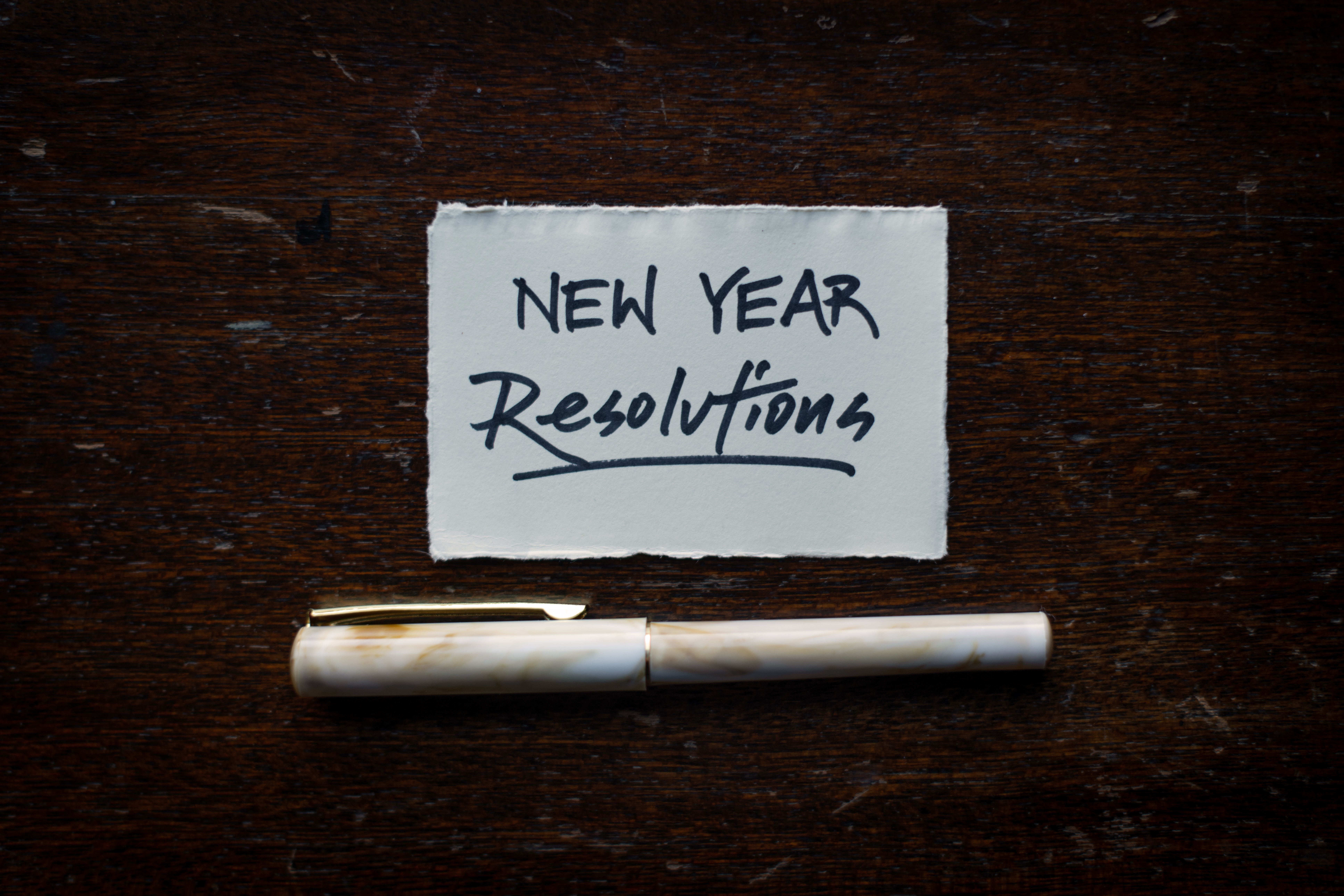 New Year Resolution written on a paper with a pen below it.